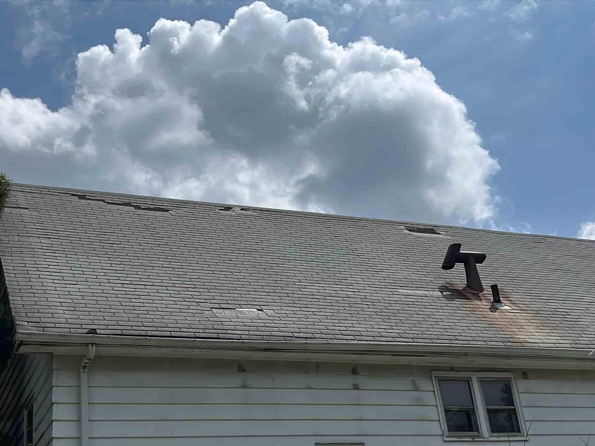 The roof of a house has a hole in it and requires emergency roofing repair.