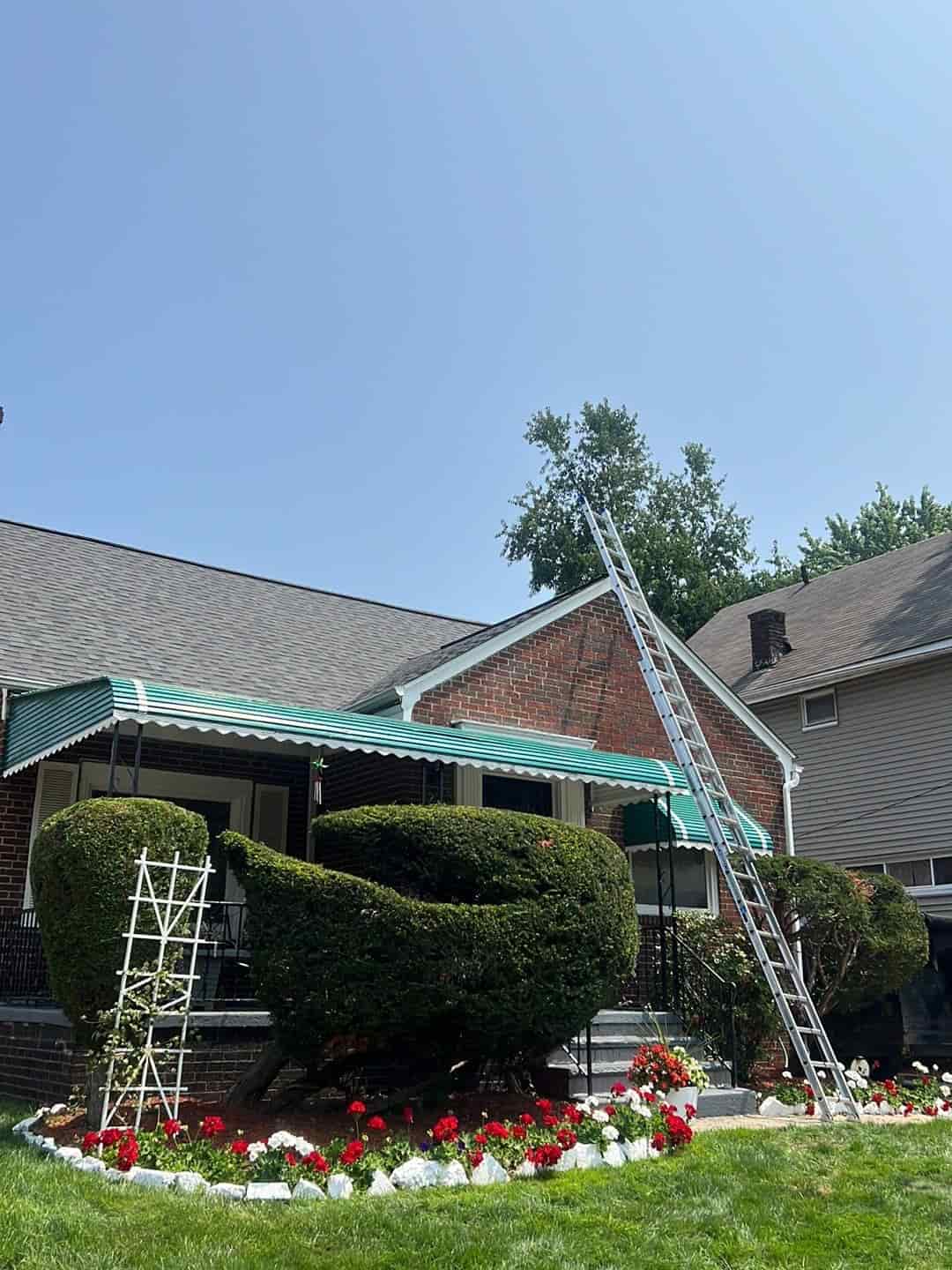 A house with a green awning and flowers, featuring a metal roof installation with a standing seam design in Ohio.
