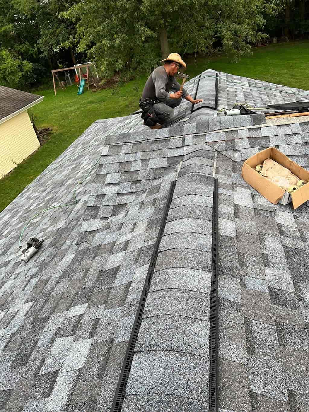 A man performing work by installing shingle on a roof.