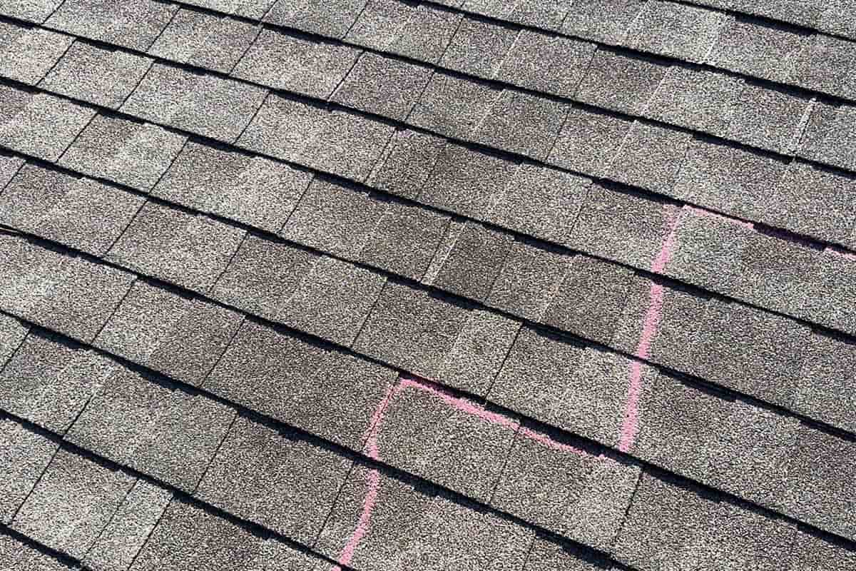 A shingled roof with a pink line on it, indicating hail damage that may result in a leak and justify the need for emergency roofing repair.