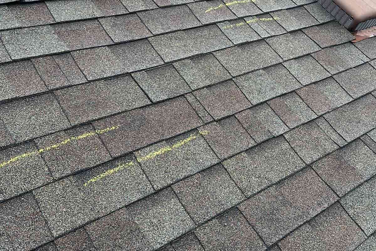 A roof with shinny shingles on it needs repair ater weather damage