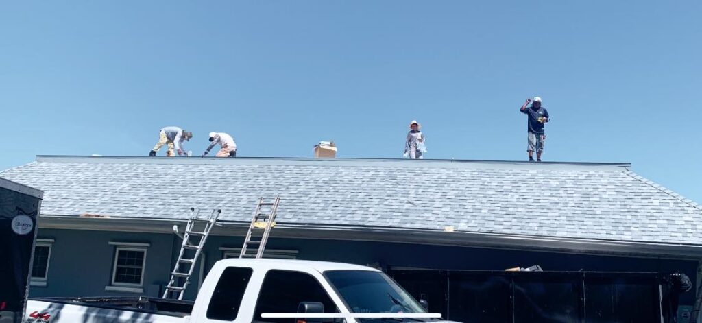 A group of men are working on the roof of a house, performing roof repairs to prevent water intrusion in Ohio.