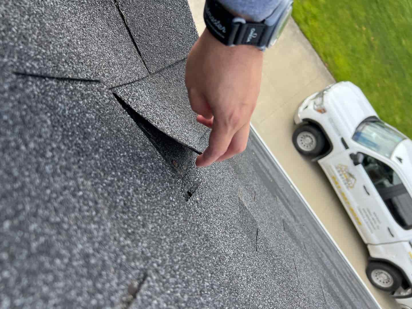 A person fixing a shattered shingle on a leaky roof.
