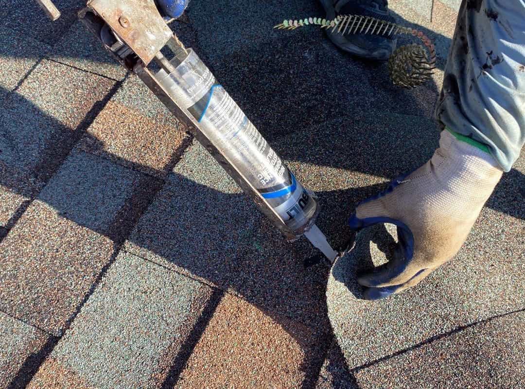 An individual utilizing a tool to repair a shingled roof damaged in Ohio.