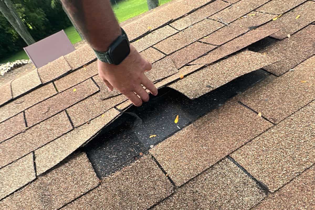 An expert conducting roof repairs to fix shingle damage caused by water intrusion.