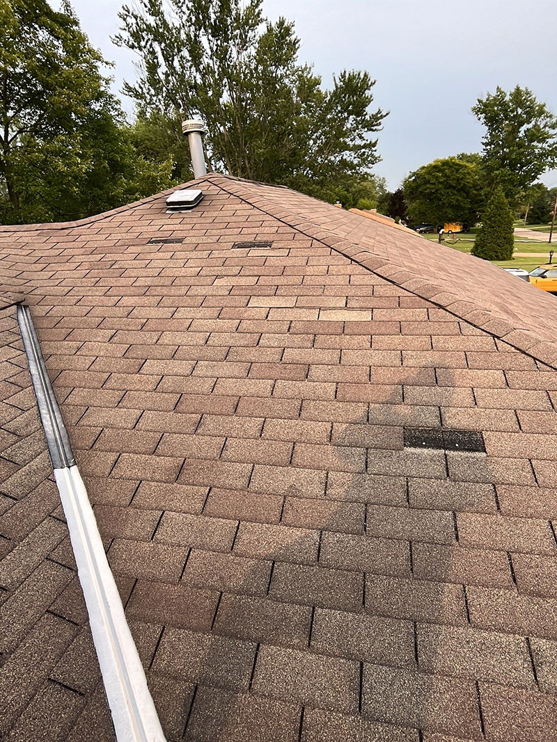 A shingled roof with a hose attached to it for efficient water drainage.