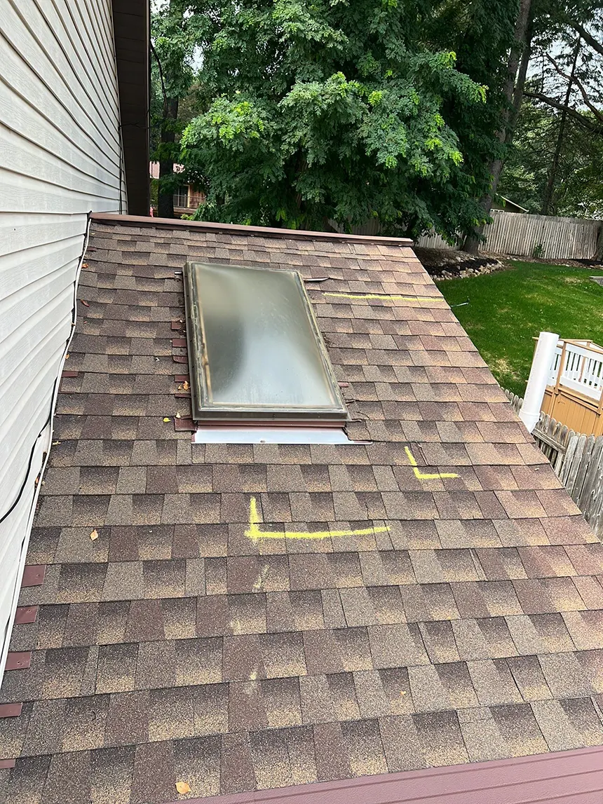 A shingled roof with an important skylight on it.