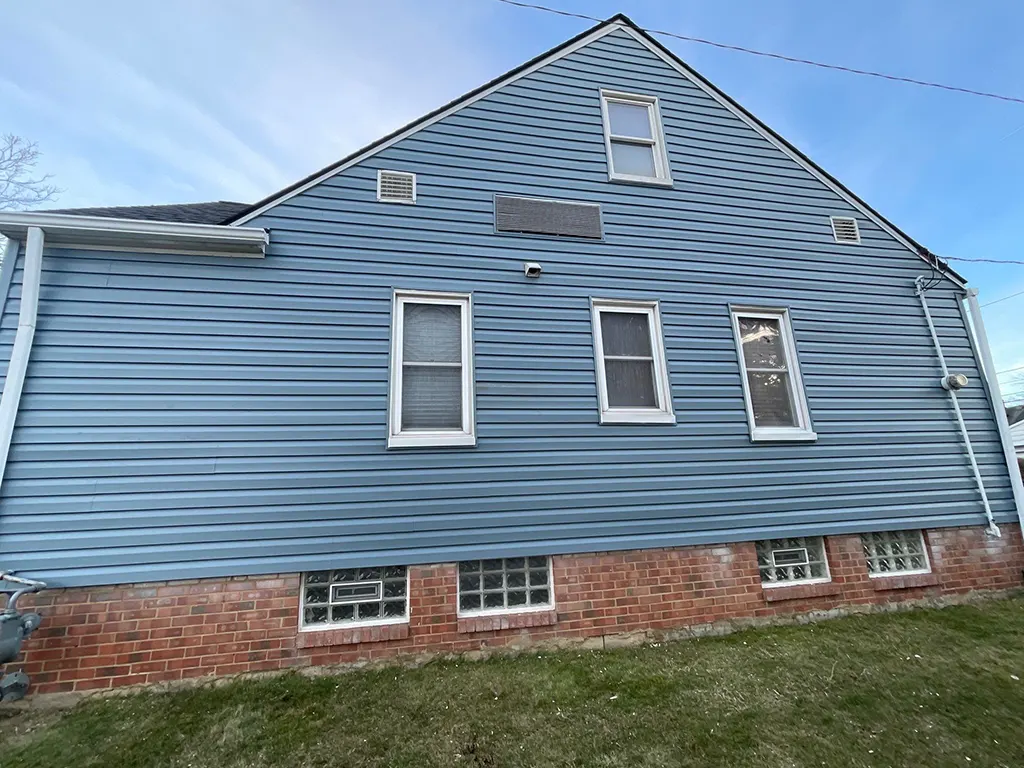 A house with blue siding and white windows that needs some work.
