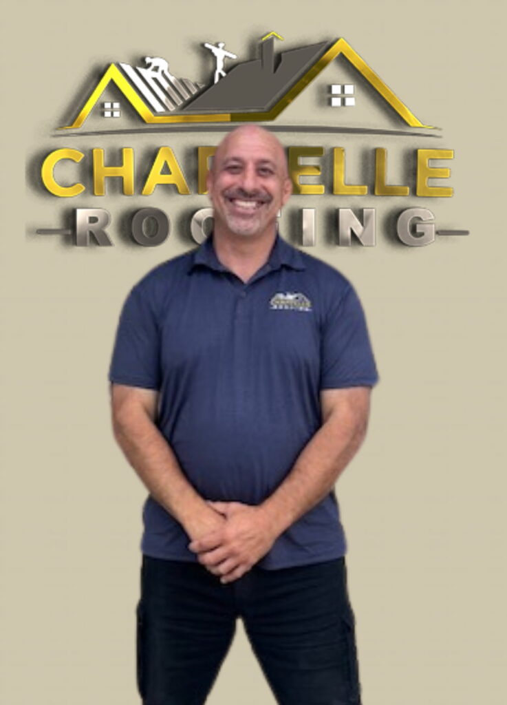Man in a navy shirt standing with arms crossed in front of a "Chapelle Roofing" sign featuring a roof graphic with workers, perfectly embodying our "About Us" commitment.
